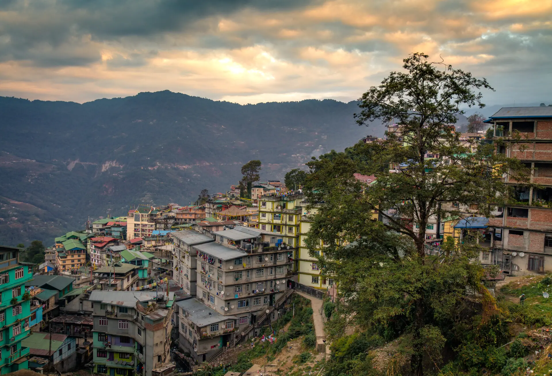 Sunset over himalayan city Gangtok, Sikkim, India with vibrant sky distant cliffs and buildings.